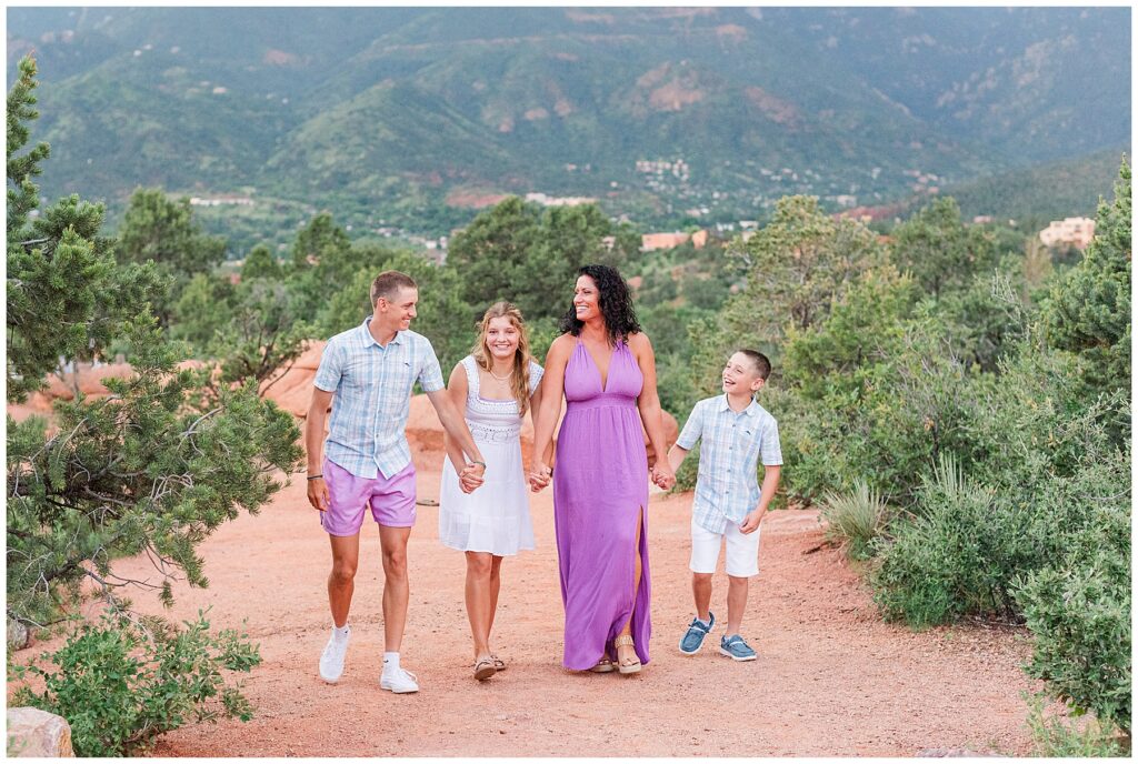 Mom and her three children walk hand-in-hand on a path in Garden of the Gods for family photos
