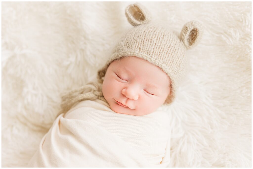 Newborn baby sleeps swaddled with a hat with ears on it for this in-home Colorado newborn session