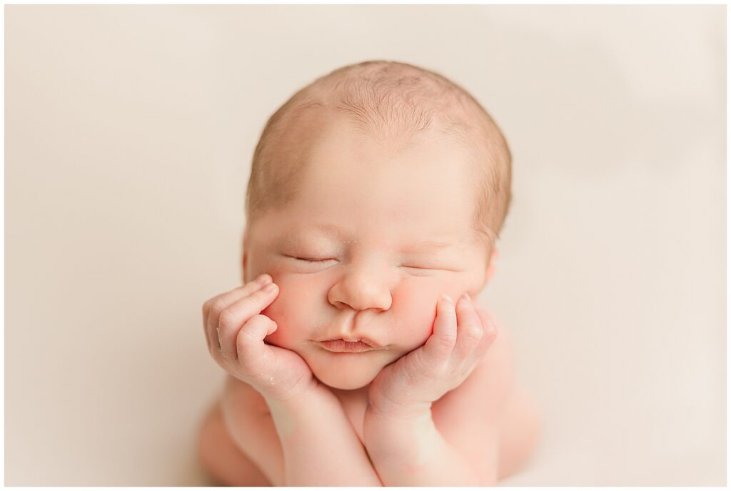 Baby boy sleeps with his hands on his cheeks for this in-home Colorado newborn session