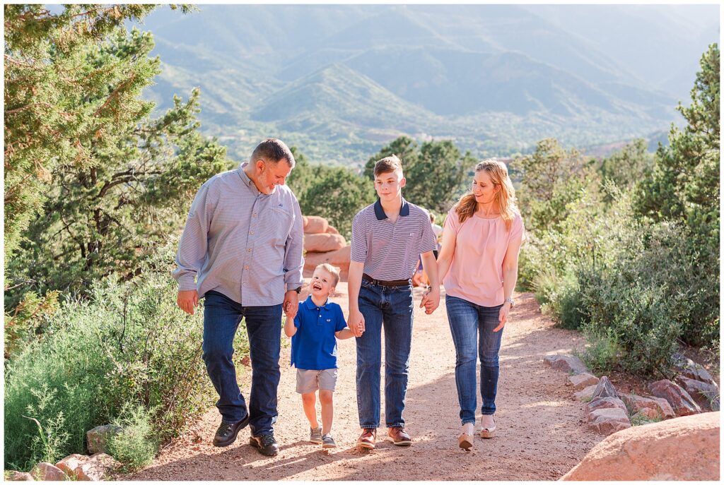 Couple along with their two sons walk up a mountain path during Dixon Outdoor Family Session at Garden of the Gods in Colorado Springs, CO