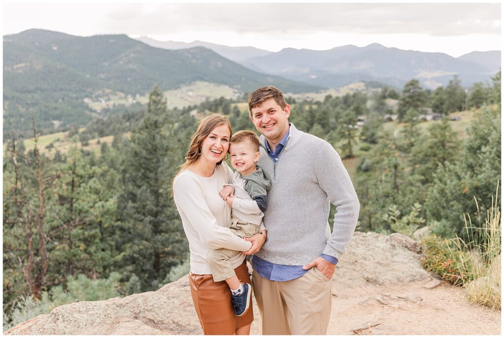 Husband and wife pose with their toddler son at the Amy Maly Family Session at Mt. Falcon in Morrison, CO