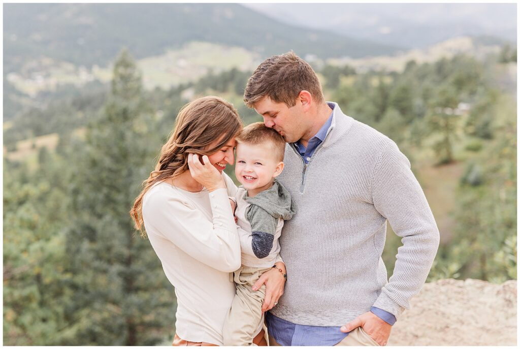 Mother holds her toddler son while the father kisses the boy's head at Mt. Falcon in Morrison, CO