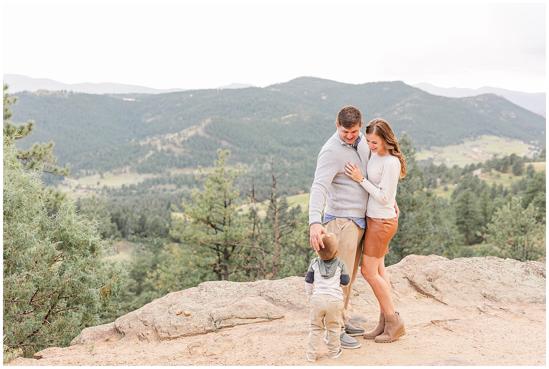 Husband and wife stand close together as their little boy looks up at them during the Amy Maly Family Session at Mt. Falcon in Morrison, CO