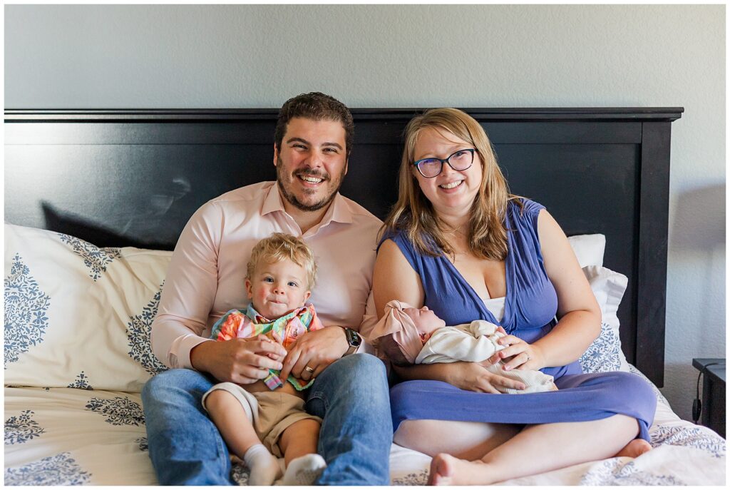 Family of four pose on the bed at home for Schwartz Family Newborn Session in Fort Collins, CO