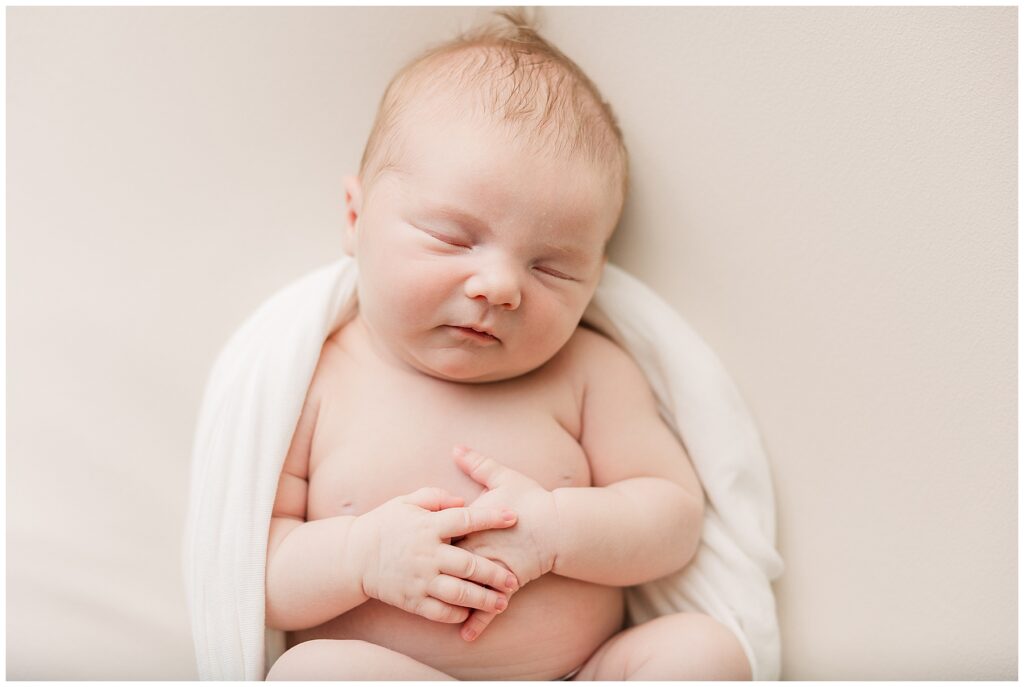 Baby sleeps with her hands folded for light and airy newborn photos
