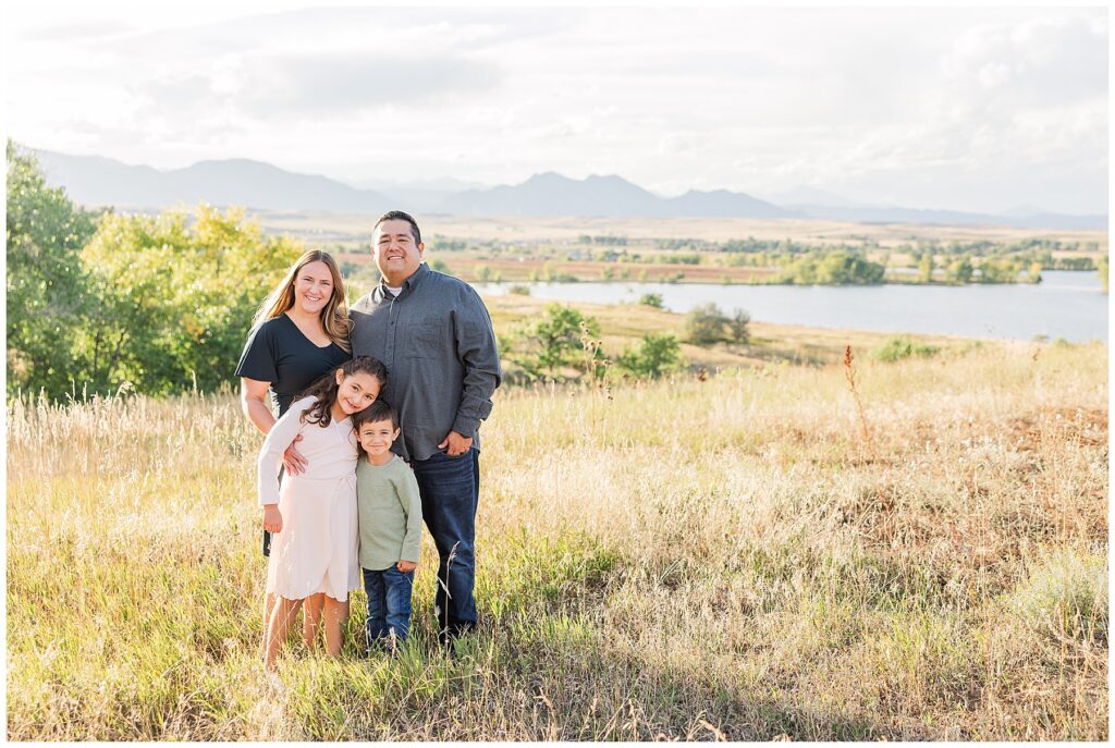 Mom and Dad stand behind their son and daughter during their Romero Family Fall Session at Standley Lake in Westminster, CO