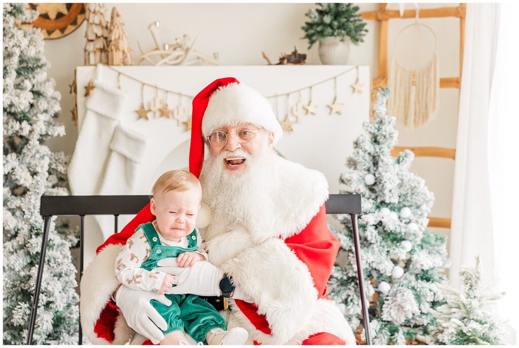 Baby cries in Santa's arms during Sugarhill Studio Santa Minis in Longmont, CO