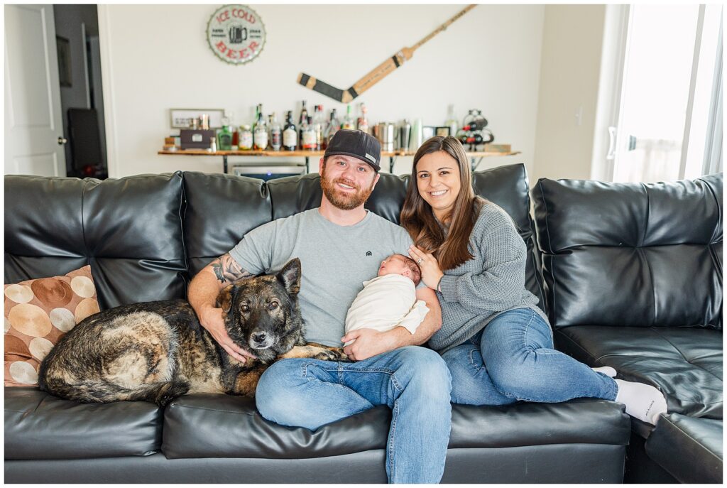 Family poses with their precious newborn baby girl on their couch in their family home