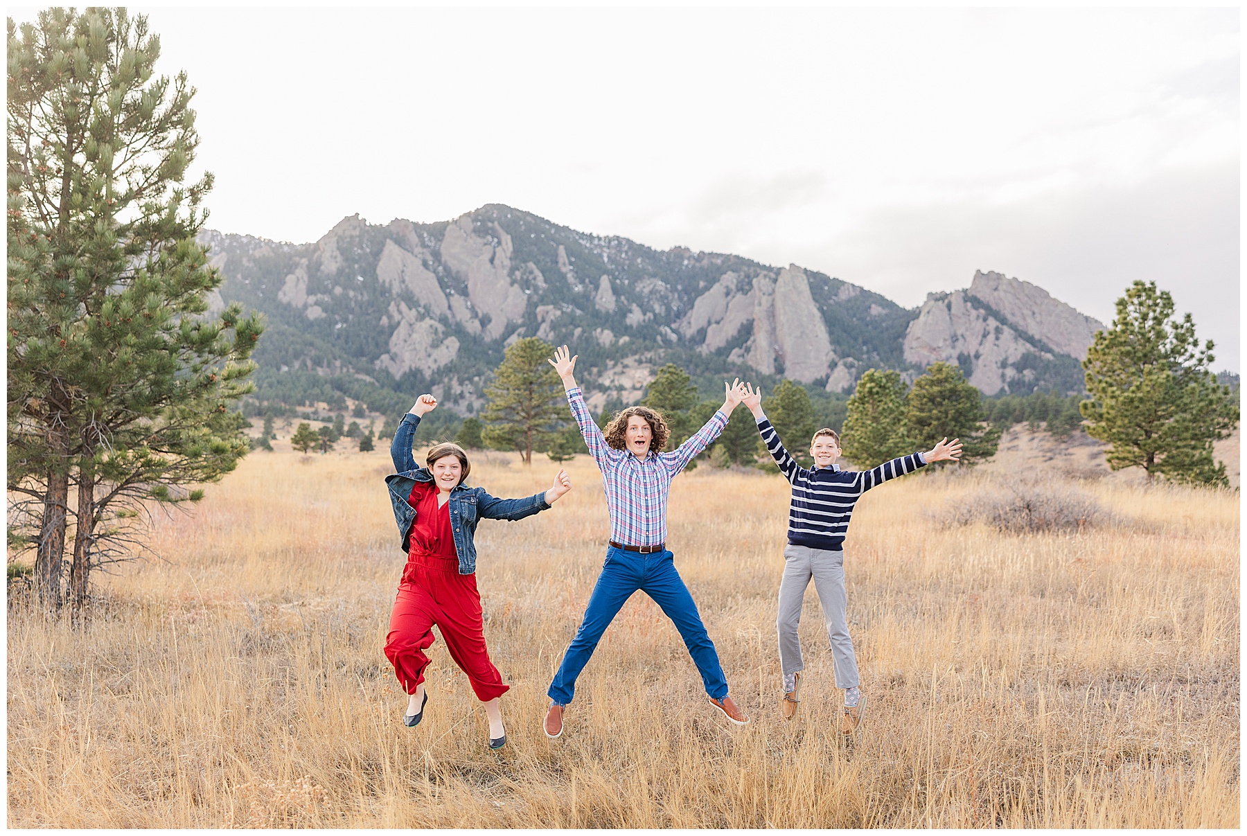 Three teenage siblings jump with their arms out during a Boulder outdoor family session
