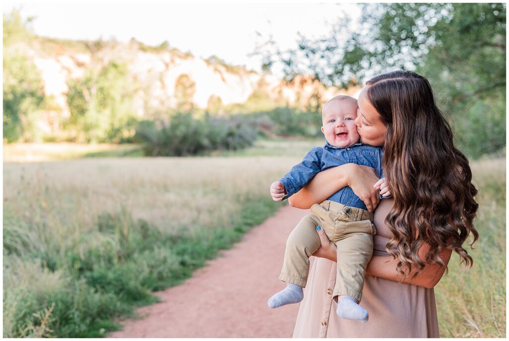 Mom kisses her baby boy on the during outdoor photos