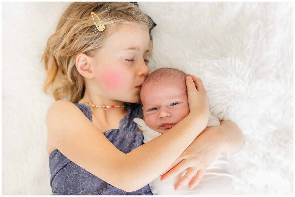 Big sister kissed her swaddled newborn brother during a musical themed newborn session