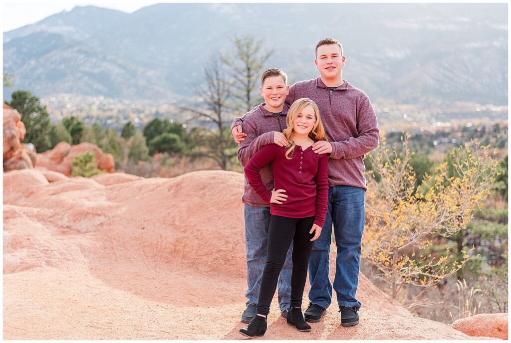 Siblings pose in front of mountains on a red rock formation