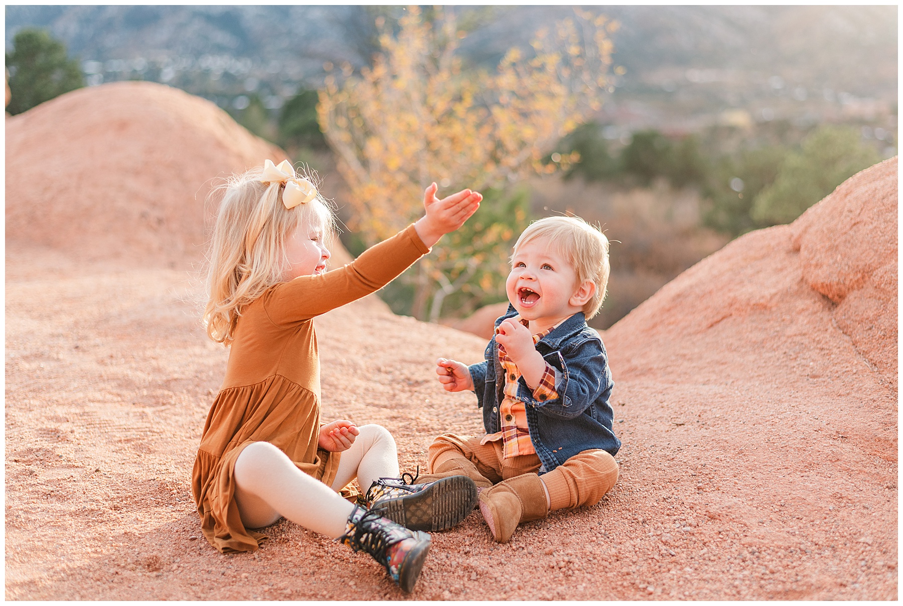 Two siblings share a moment laughing while sitting on the ground at Garden of the Gods