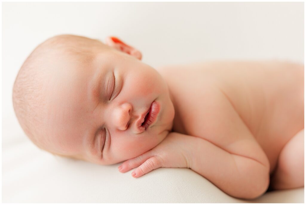 Baby sleeps on her side with her hand under her chin during a Denver indoor newborn session
