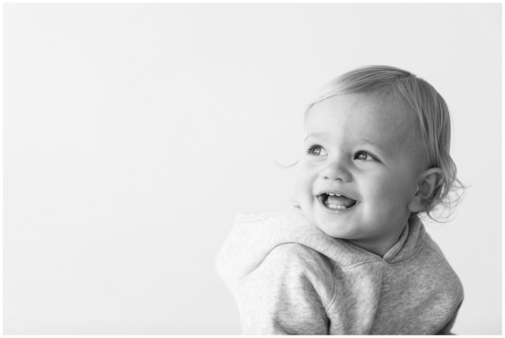 Baby looks away from the camera smiling for Catherine Chamberlain Photography