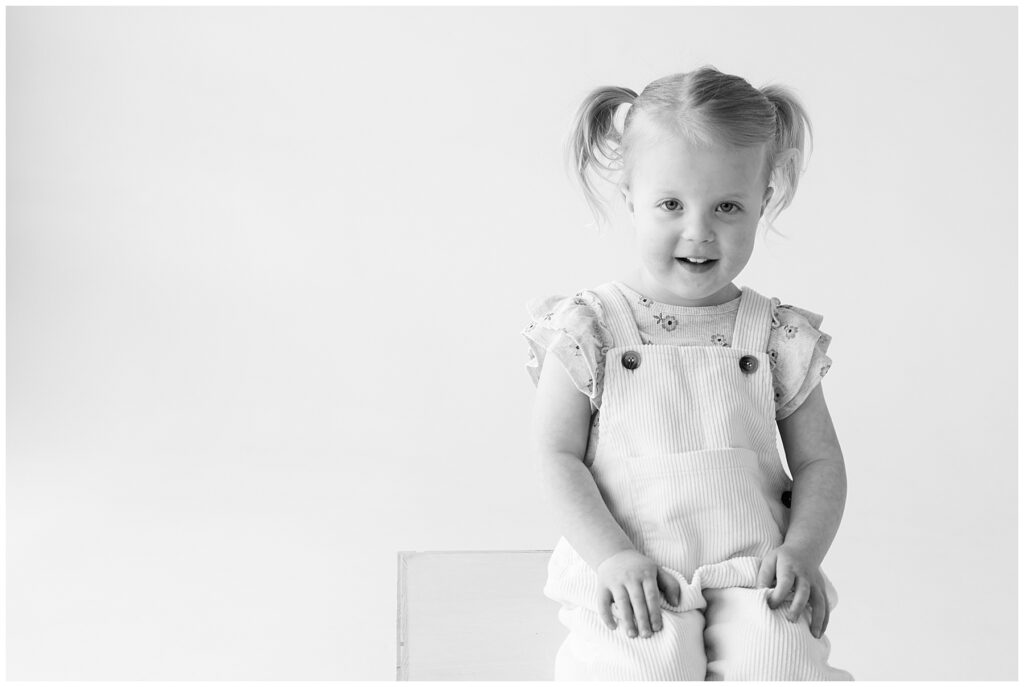 Little girl in pigtails and overalls sits for personality portraits in Northern Colorado