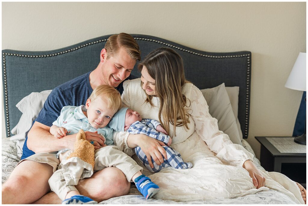 Family of four get candid shot on the bed while featured in an educational blog for newborn session safety considerations