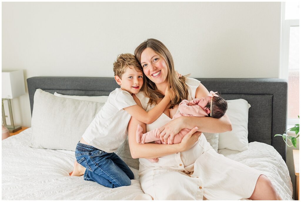 Mom snuggles with toddler boy and newborn for in-home lifestyle photos in Northern Colorado