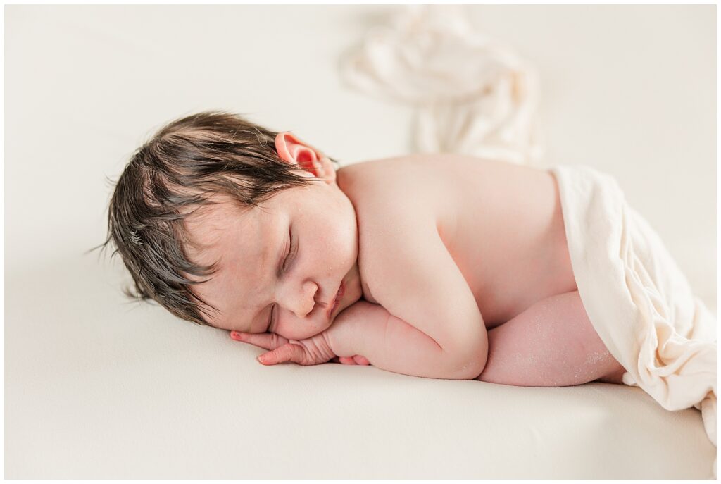 Baby sleeps on her hands with a neutral background for light and airy photos