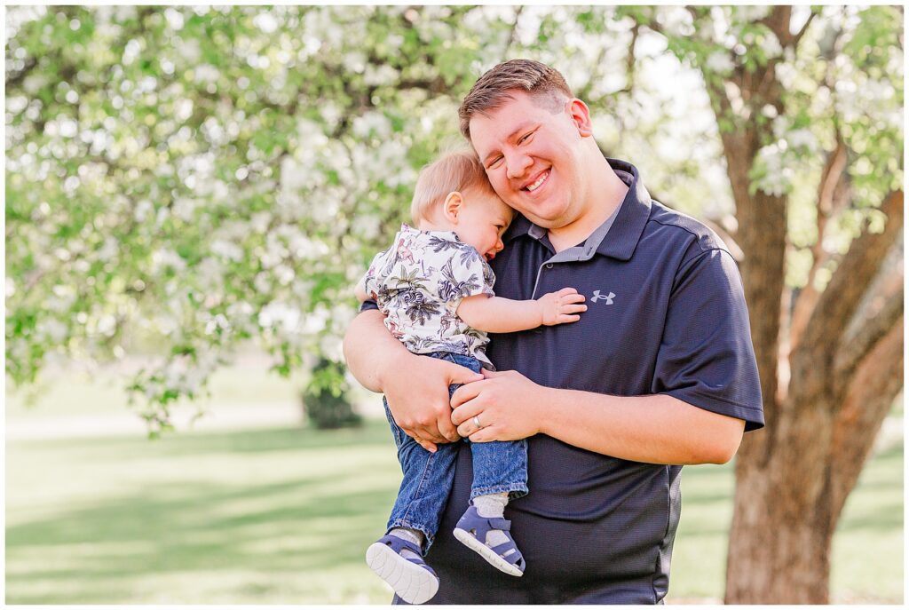Baby snuggles dad's neck during light and airy outdoor family photos