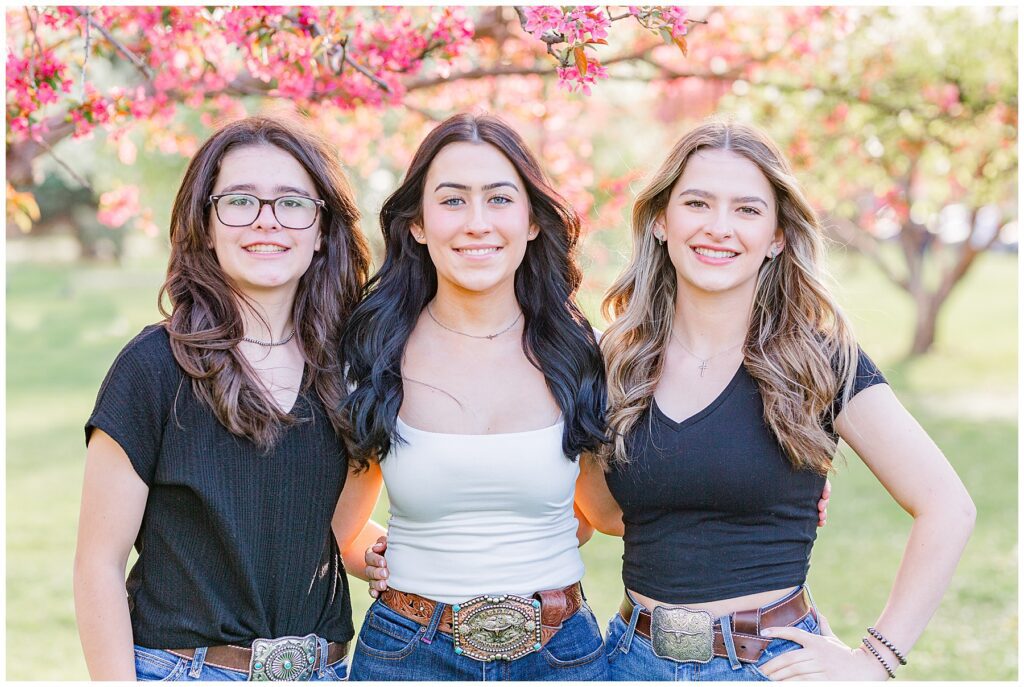 Three sister pose with blossoms in Colorado during the spring