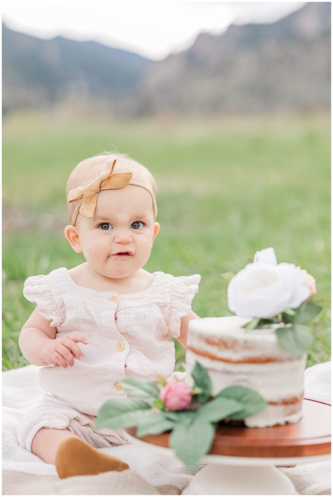 Baby girl looks at the camera during a light and airy outdoor smash the cake session 