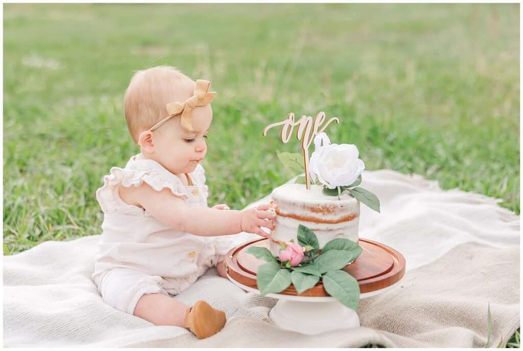 one-year-old reachers for her beautiful cake in Boulder, CO outdoors in the spring season