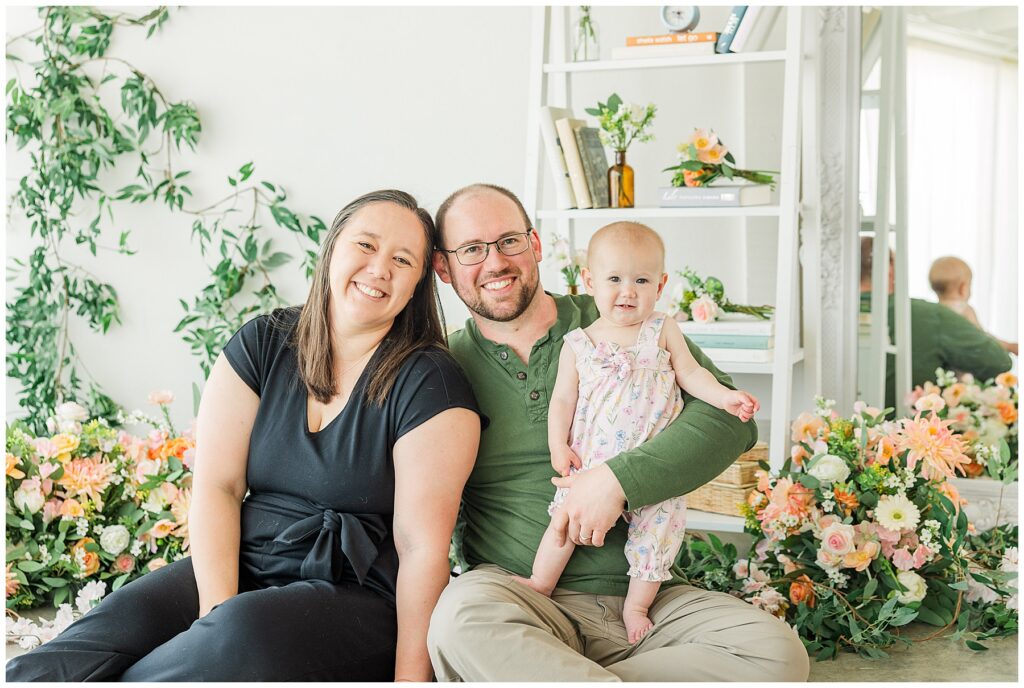 Family of three pose for light and airy photos in a studio decorated for spring