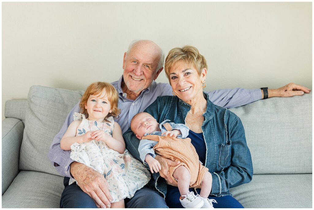Grandparernts pose with their two grandkids on the couch