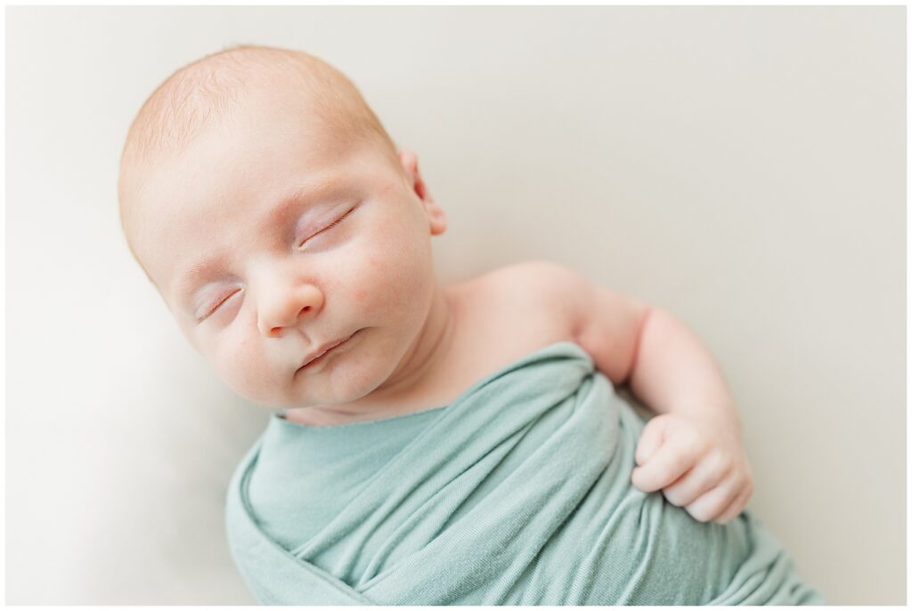 Newborn sleeps while swaddled for in-home lifestyle photos and is featured in a blog discussing the importance of print