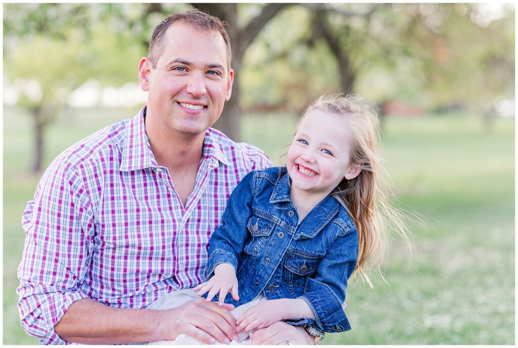 Daughter and father smile for the camera during this outdoor spring family session