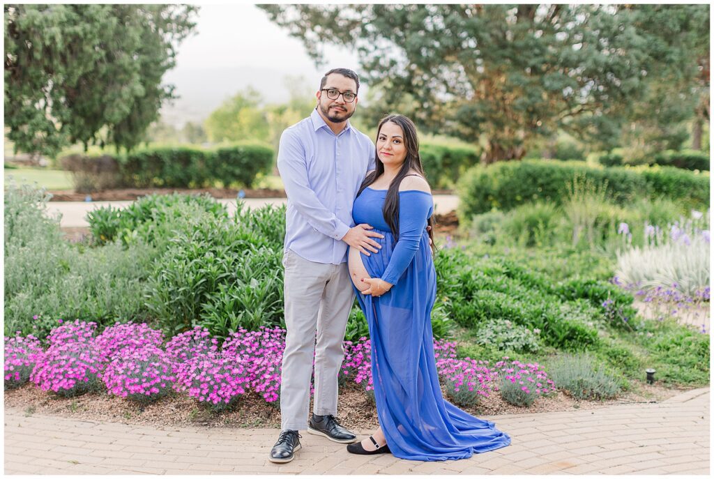 Expecting couple take a photo in the garden while featured on a blog about an ideal time to take maternity photos