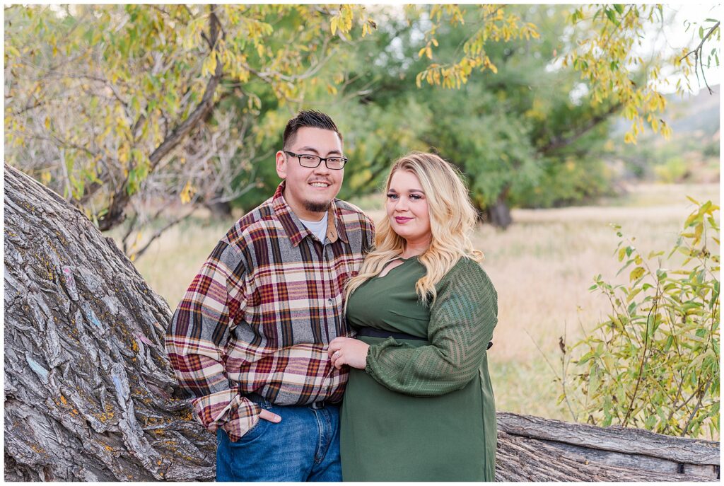 Parents pose with a hand in the husbands pocket and her hand on him as well