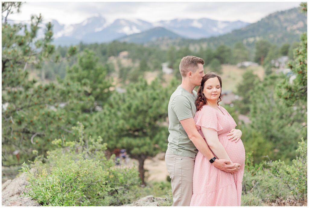 Couple pose during a maternity session with mountains in the background