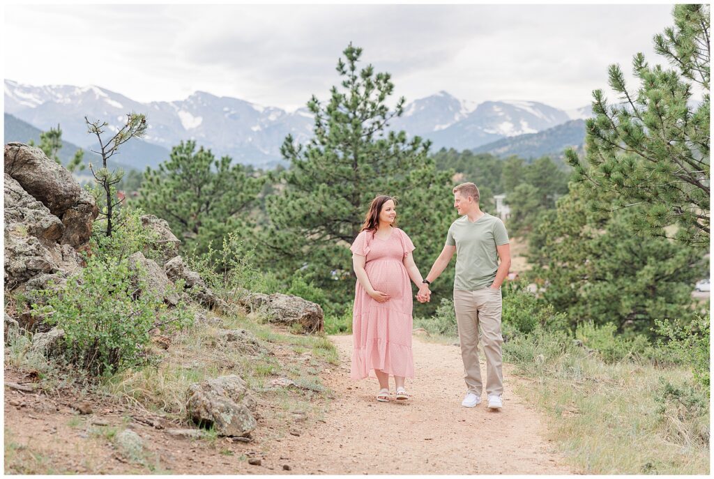 Expecting couple walk hand in hand down a path for outdoor maternity photos