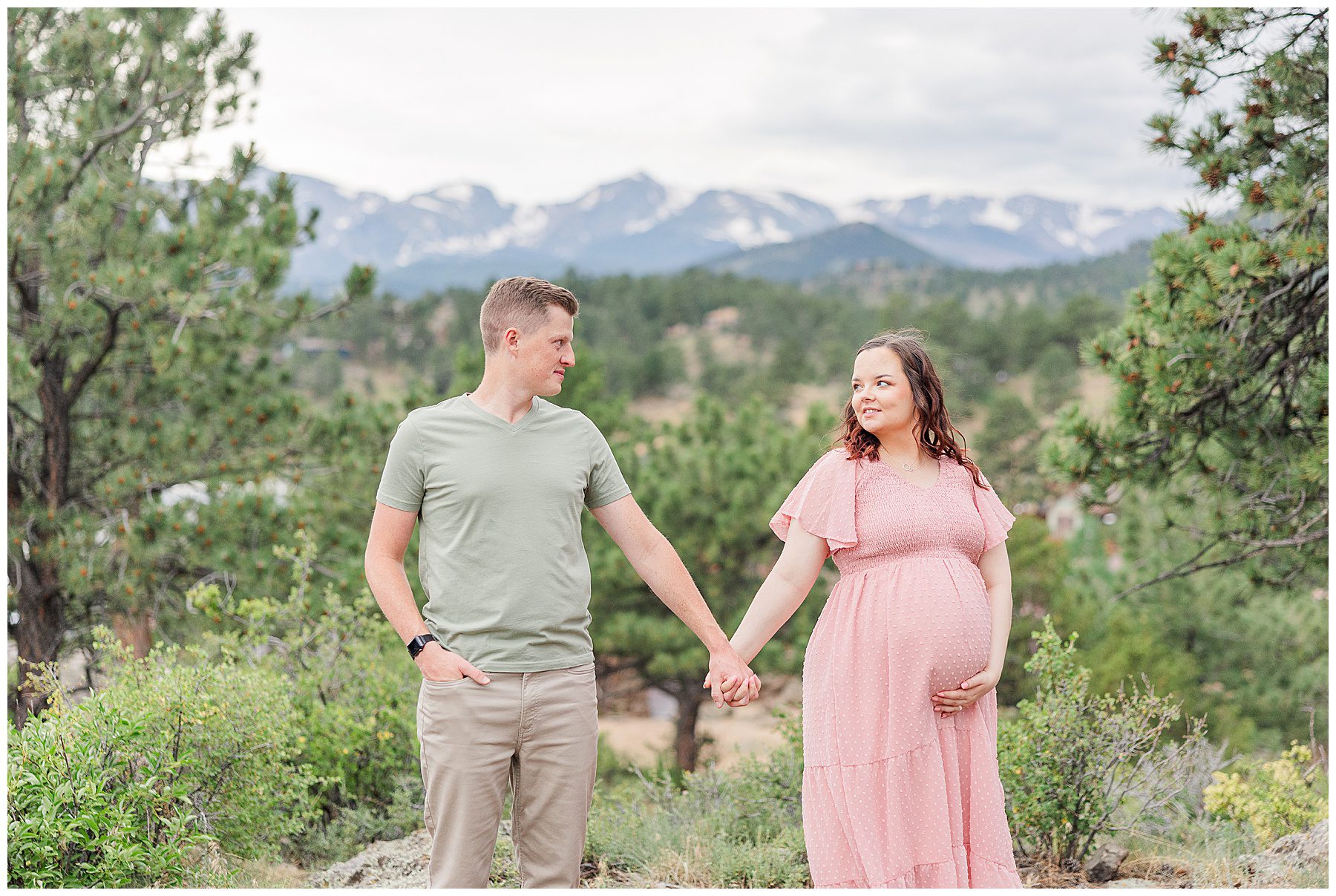 Expecting couple hold hands and look at each other during a Stanley Hotel Maternity Session in Estes Park, Colorado