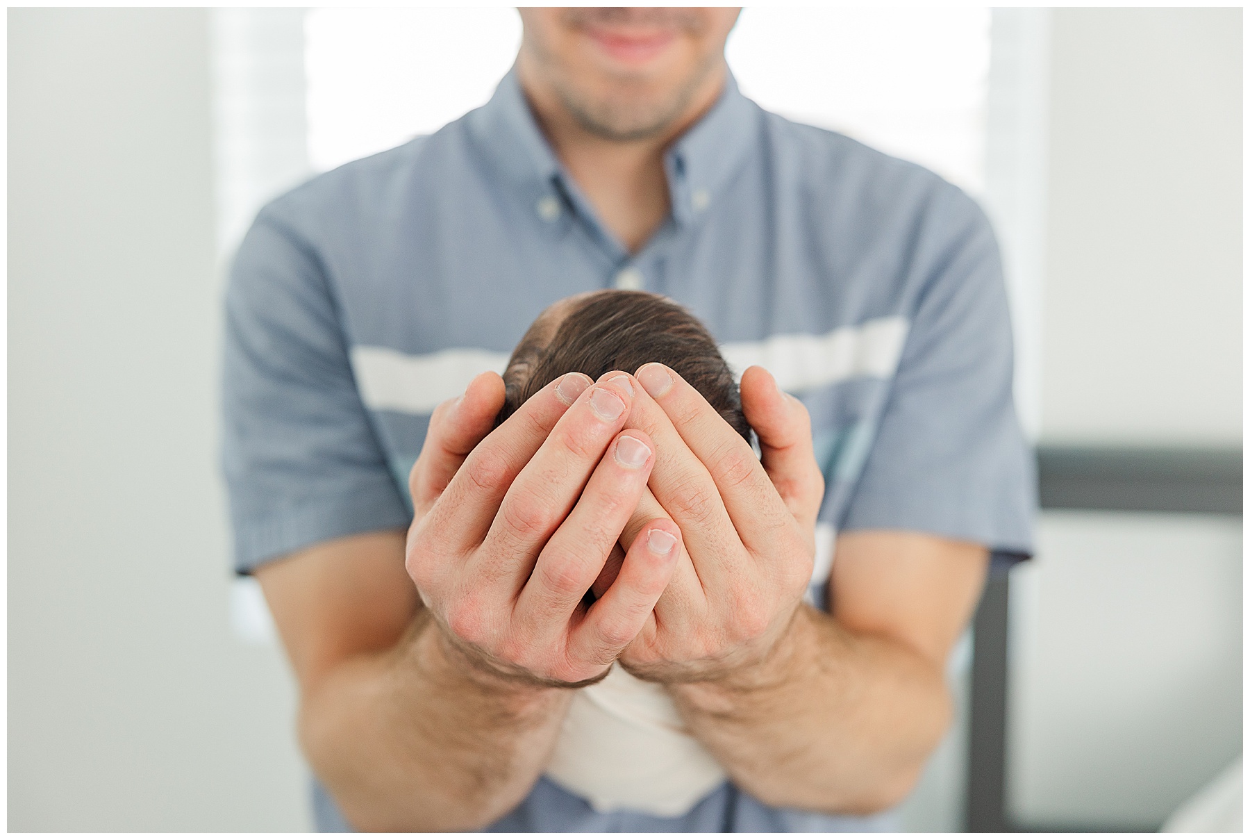 Dad holds baby in his forearms 