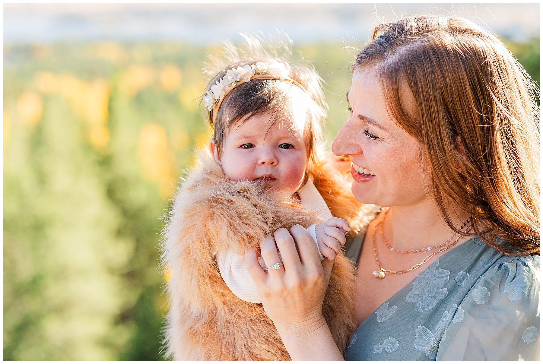 Mom looks at her baby who is looking right into the camera for fall family photos in Northern Colorado