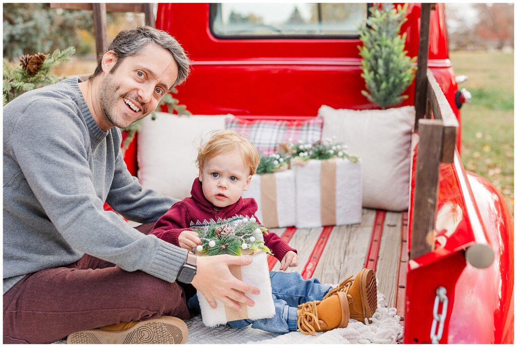 Dad hands baby a gift during Christmas minis