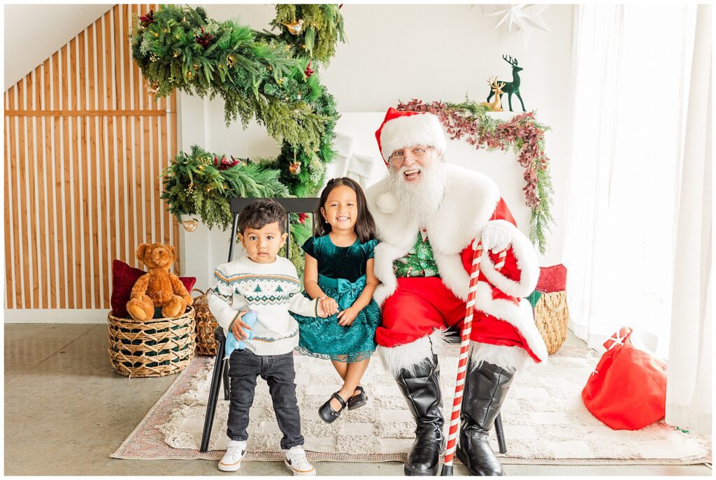 Little kids poses with smiling Santa in Longmont, Colorado