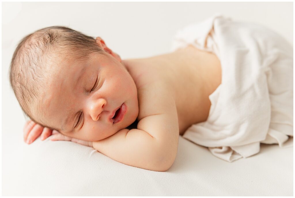 Baby sleeps with cheek resting on his arm during at home newborn session in Northern Colorado