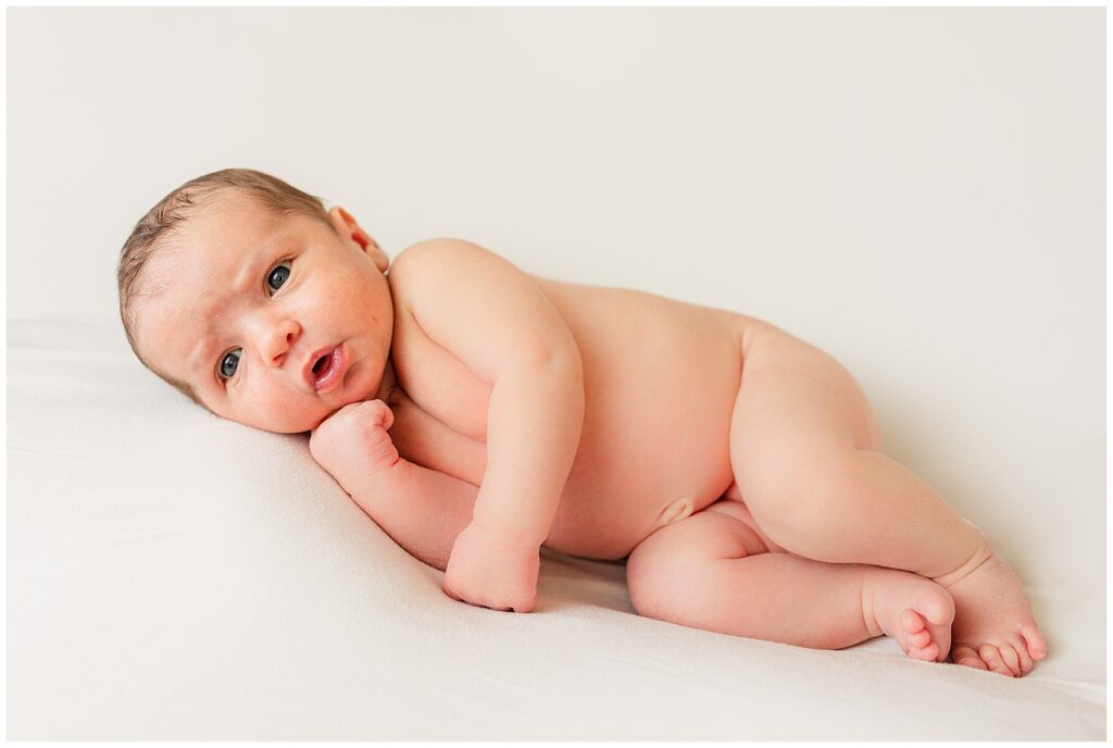 newborn puts hand under chin during a lifestyle newborn session in the Denver area with Catherine Chamberlain Photography