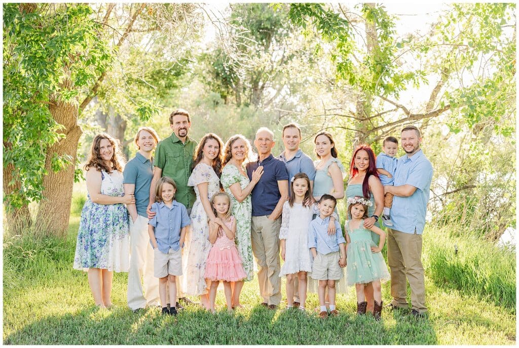 Light and airy outdoor extended family shot in pastel colors with green trees